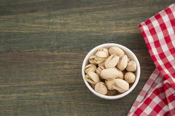 Pistachios in the bowl on wooden background