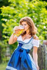 Woman in traditional bavarian dress holding mug of beer