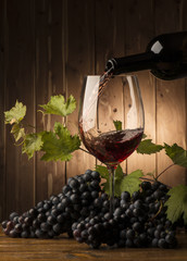 Naklejki  Kieliszek z czerwonym winem i winogronem na drewnianym stole
