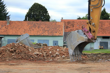 Fototapeta premium Baggerschaufel auf einer Baustelle (Haus wird abgerissen)