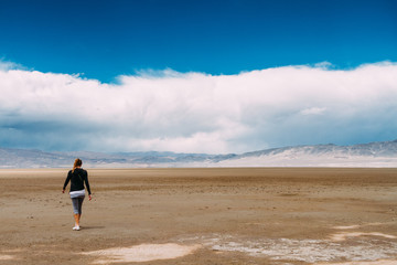 Obraz premium Redhead woman walks back in a desert with mountains ahead in Cat