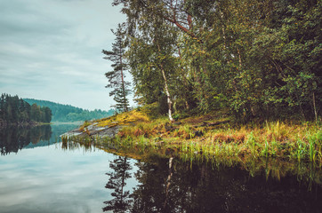 Beautiful autumn landscape with lake, pine trees, natural stone coast in the Republic of Karelia, Ladoga , northern region in Russia. Fall forest, russian tourism and travel concept.