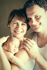 Portrait of couple with newborn daughter, happy family. Mother, father and child together.