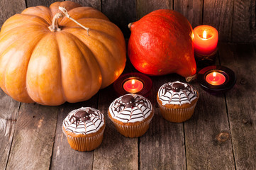 Halloween pumpkin and funny cupcakes with spiders on old rustic wooden boards. Halloween background
