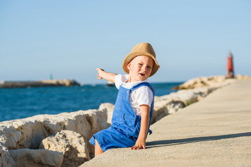 Fototapeta na wymiar Cute blond boy in hat and blue overall