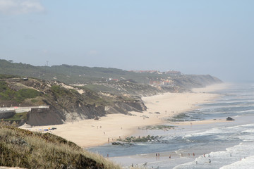 Light fog covers foamed sea and white sand