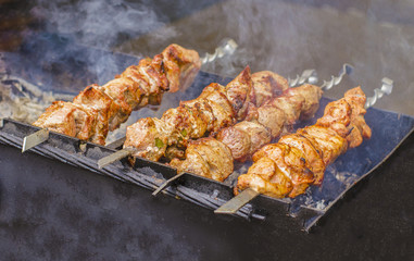 closeup of some meat skewers being grilled in a barbecue.