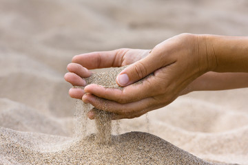 sand running through hands of woman