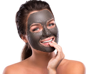 Beautiful woman with a clay or a mud mask on her face