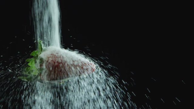 Closeup of sugar pouring onto strawberry