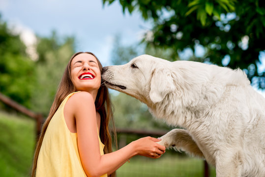 Young and happy woman playing with Maremma italian sheepdog on the lawn in the countryside in Tuscany