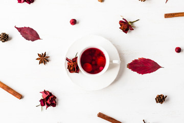cup of fruit tea with autumn leaves, cinnamon sticks, star anise, cones, dry roses, top view, flat lay