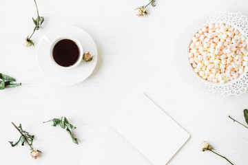 Workspace with notebook, cup of coffee and dried rose flowers. Top view, flat lay