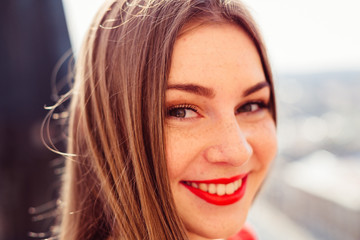 Closeup of beautiful girl's face with red lips and freckles arou