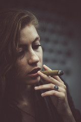 Tired woman holds Cuban cigar before her opened mouth