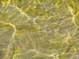 Fototapeta na wymiar Smooth ripples, waves on surface of transparent yellow water