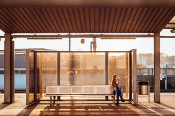 Lonely girl sits on the steel bench waiting for someone