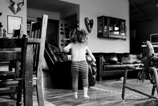 Young girl jumping in living room, black and white 