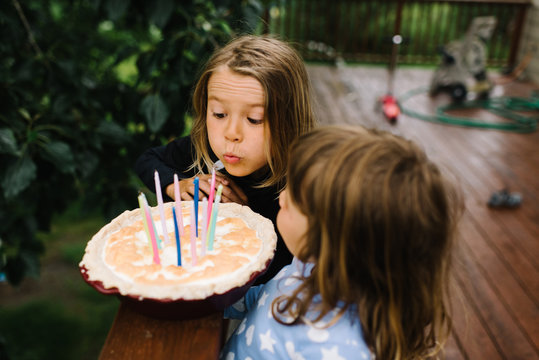  Two young girls blowing out candles on a cake 