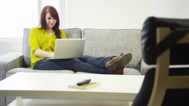 Young woman with laptop sitting in living room
