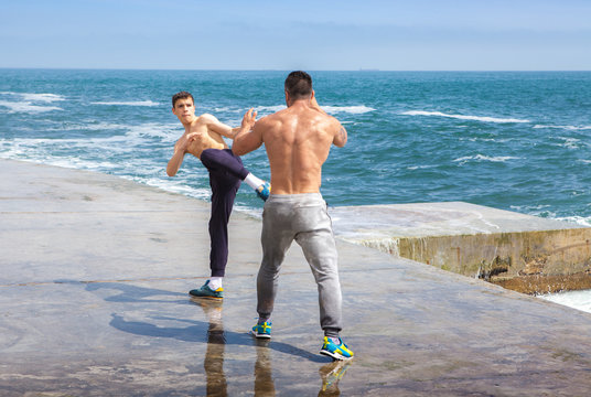 trainer and the pupil engaged on karate near the sea