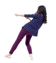 back view of standing girl pulling a rope from the top or cling to something. Long-haired curly girl in a striped blouse pulling a rope.