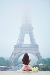 Parisian woman in front of the Eiffel tower - obrazy, fototapety, plakaty