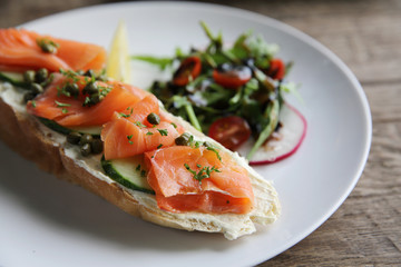 smoked salmon on toasted bread with cream fresh, lemon and salad