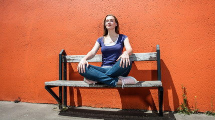 relaxing young woman enjoying meditating on bench in yoga position