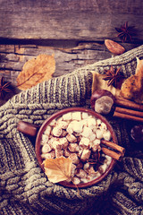 Hot cocoa with marshmallows with spices on the old wooden boards. Coffee, cocoa, cinnamon, nuts, star anise, cozy sweater.Autumn Still Life