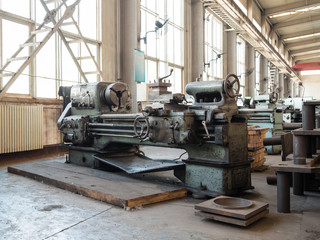 Old turning lathe is in a dirty shop floor without the people