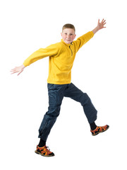 Young red-haired boy in a yellow jacket jumping with arms outstretched on a white background