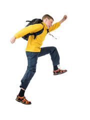 Young red-haired boy in a yellow jacket and a backpack boy jumping with arms outstretched on a white background