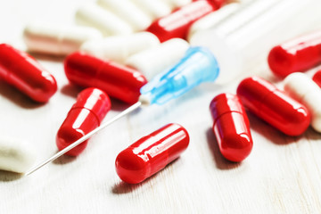 Drug in red and white capsules, empty syringe for injections on