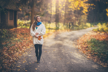 Young woman walking in the beautiful forest at autumn
