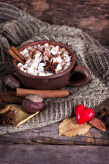 Hot cocoa with marshmallows with spices on the old wooden boards. Coffee, cocoa, cinnamon, nuts, star anise, cozy sweater.Autumn Still Life