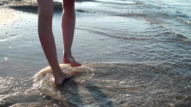 barefoot walk on the wet sand, sunset Beautiful slim legs, warm summer sea, beautiful legs, woman goes barefoot on the coast sea. romantic walk on the beach, walk at dawn, sunset,