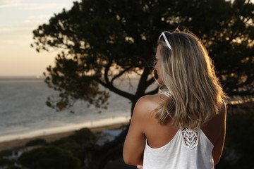 Mujer mirando el mar al atardecer.