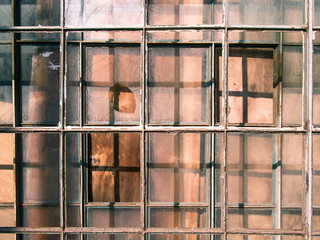Old wooden window frame with a square lattice and broken glass