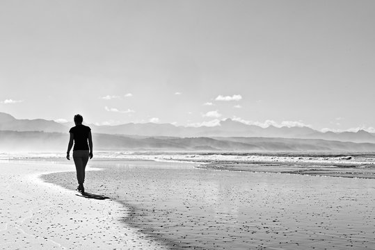 Spiaggia deserta in bianco e nero con ragazza che cammina