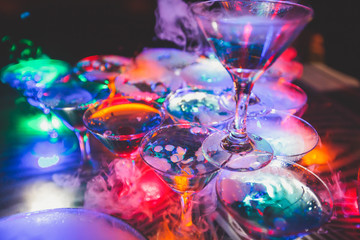 Beautiful row line of different colored alcohol cocktails on a party, martini, vodka,and others on decorated catering bouquet table on open air event, picture with beautiful bokeh  