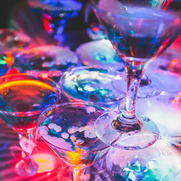 Beautiful row line of different colored alcohol cocktails on a party, martini, vodka,and others on decorated catering bouquet table on open air event, picture with beautiful bokeh
