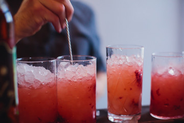 Beautiful row line of different colored alcohol cocktails on a party, martini, vodka,and others on decorated catering bouquet table on open air event, picture with beautiful bokeh
