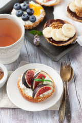 Bagels with different toppings - with cream cheese, figs, bananas, chocolate and blueberries for breakfast on a board