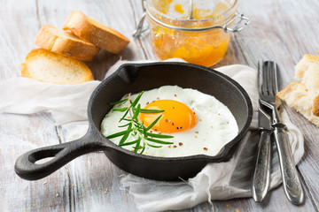 Pan of fried egg, crispy baguette and fruit jam