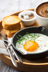 Pan of fried egg, cup of coffee baguette and jam