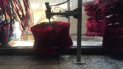 Slow motion footage of the flopping mops and spinning brushes of a busy carwash.
