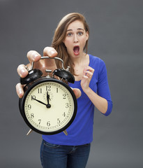 scared beautiful young woman standing with a clock for stressful deadlines