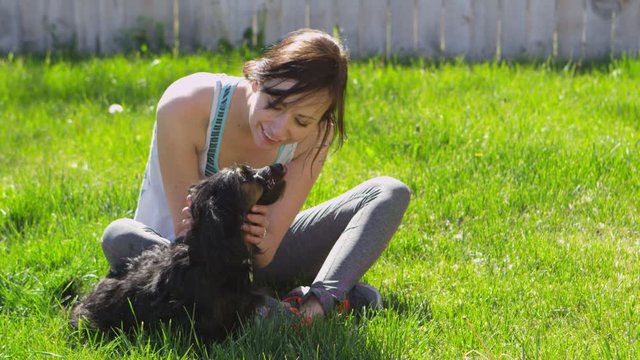 Slow motion woman playing with small black dog