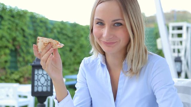 Pretty girl sitting in the restaurant and eating pizza
